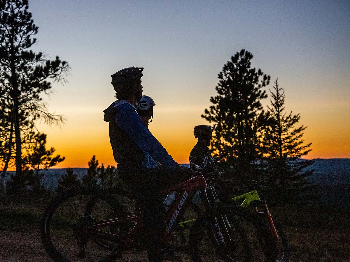 Three mountain bikers watching the sunset.