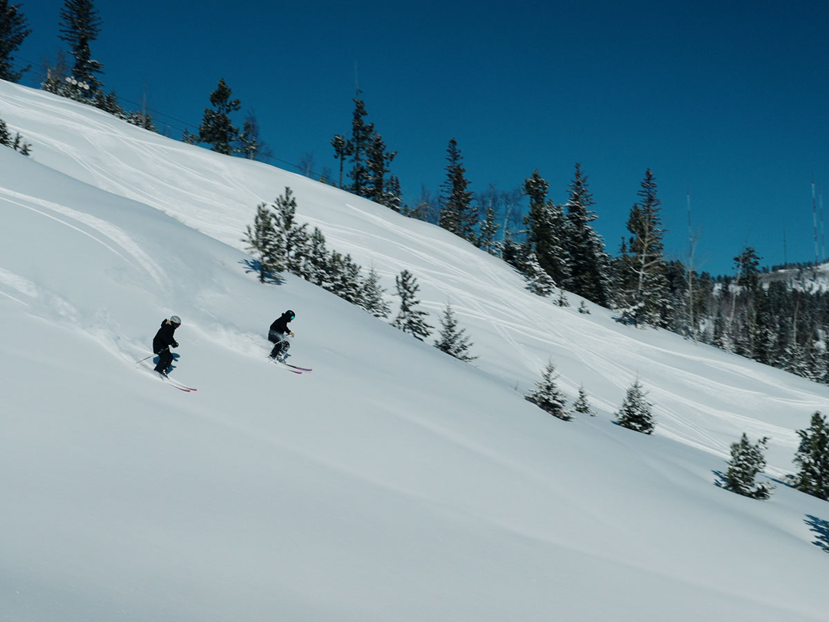 Two people skiing down a mountain.