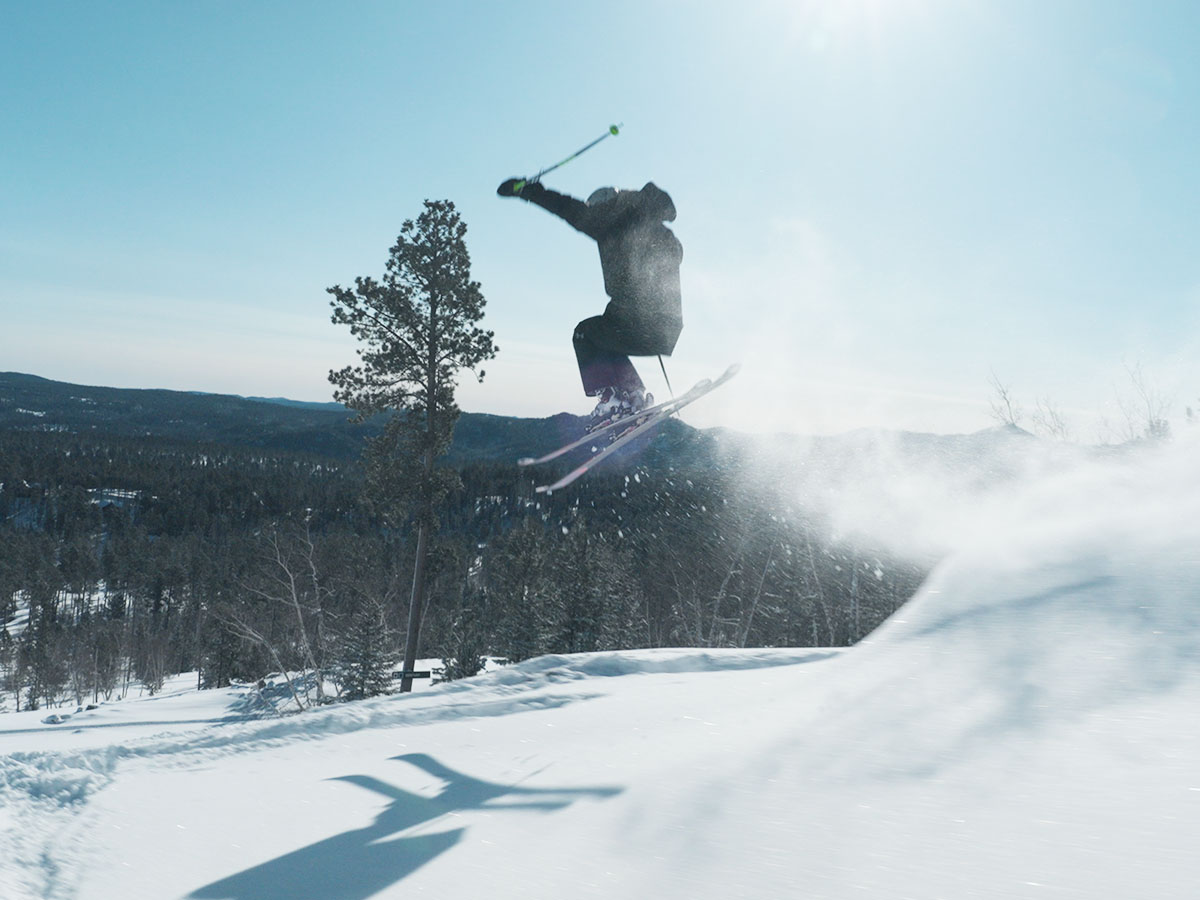 A skier mid air jumping off a slope.