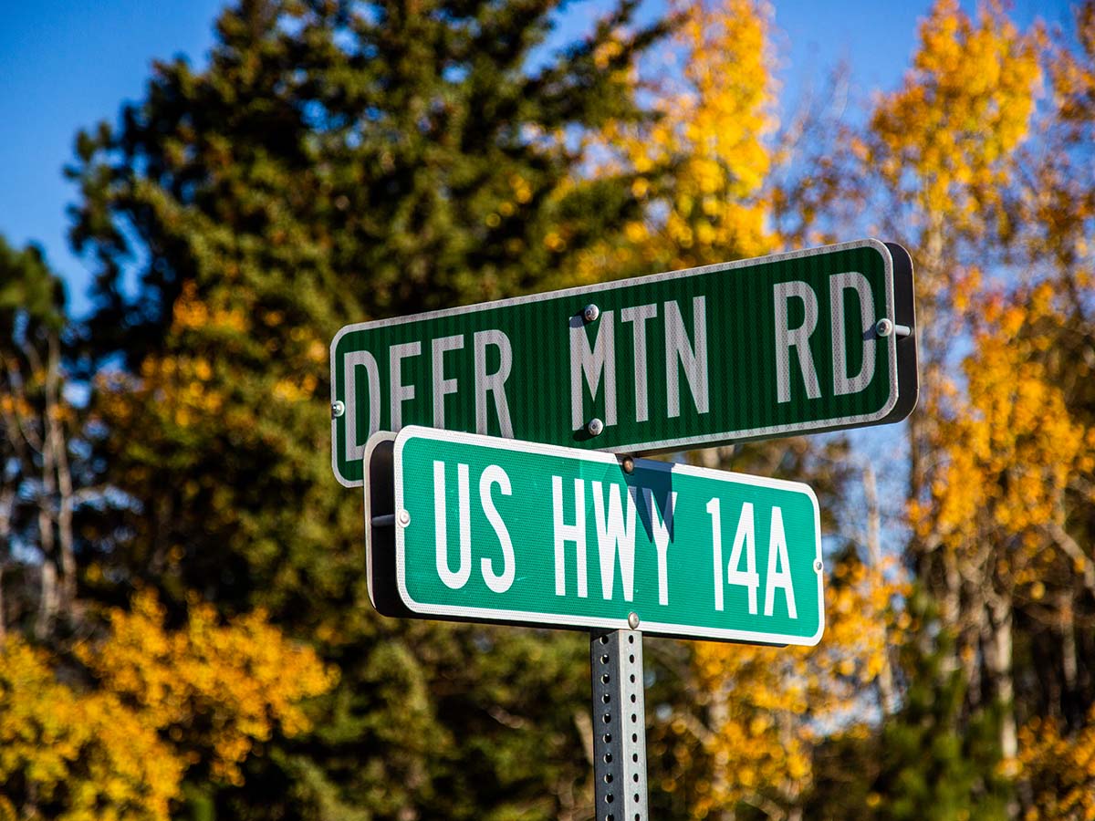 Street sign for Deer Mountain Village road and US Highway 14A.