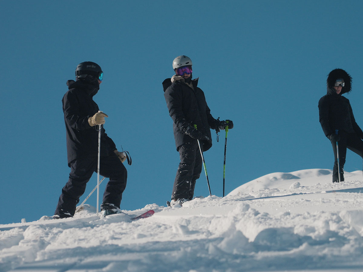 A group of people standing on a mountain ready to ski.